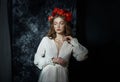 Romantic spring portrait of a young blonde woman with a wreath of red rose flowers, a girl in a light white dress. A woman with Royalty Free Stock Photo