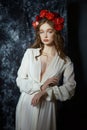 Romantic spring portrait of a young blonde woman with a wreath of red rose flowers, a girl in a light white dress. A woman with Royalty Free Stock Photo