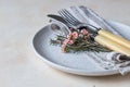 Romantic or spring table setting. Knife and fork, little pink flowers and linen napkin on a plate, light concrete background Royalty Free Stock Photo