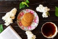 Romantic still life with lilac flowers. cup of black tea, open book and couple of oat cookies on dark wooden background Royalty Free Stock Photo