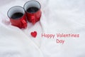 Romantic still life, two red cups of coffee on a white plaid. Valentine`s Day lettering, holiday card Royalty Free Stock Photo