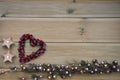 Christmas photography with silver and gold colored acorn tree ornament on natural rustic wood background with red berry love heart