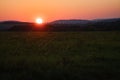 romantic sunset behind a hill in front of a meadow Royalty Free Stock Photo
