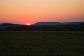 romantic sunset behind a hill in front of a meadow Royalty Free Stock Photo