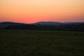 romantic sunset behind a hill in front of a meadow Royalty Free Stock Photo