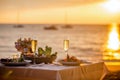 Romantic sunset dinner on the beach. Table set for two with luxurious food, glasses of champaign drinks in a restaurant Royalty Free Stock Photo