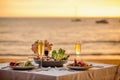 Romantic sunset dinner on beach. Table honeymoon set for two with luxurious food, glasses of champagne drinks in Royalty Free Stock Photo