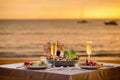 Romantic sunset dinner on beach. Table honeymoon set for two with luxurious food, glasses of champagne drinks in Royalty Free Stock Photo