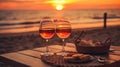Romantic sunset dinner on the beach. Table honeymoon set for two with luxurious food, glasses of rose wine drinks in a restaurant Royalty Free Stock Photo