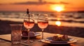 Romantic sunset dinner on the beach. Table honeymoon set for two with luxurious food, glasses of rose wine drinks in a restaurant Royalty Free Stock Photo