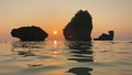 Romantic sunset at Indian Ocean Coast. Rock stones rise above the water, ripples on sea surface and reflection of cliff