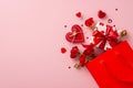 Top view shot of paper bag with themed giftbox, adorned with love-patterned paper. Red roses, heart-shaped on pink backdrop Royalty Free Stock Photo