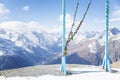 A romantic swing high in the mountains at a ski resort. Blue wooden arch with flowers. Active lifestyle and sports