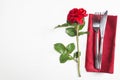 Romantic table setting with red rose and beautiful cutlery on red napkin. Royalty Free Stock Photo