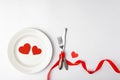 Romantic table setting on white background. Valentines day card template. Red ribbon, plate, silverware, vintage fork