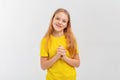 Romantic teen girl daydreaming, looking at camera with dreamy lovely gaze, wears yellow t-shirt, looks happy, stands over white