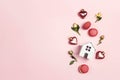 Romantic top down composition with miniature toy house, rose flowers, gift, macarons and decorative hearts on pink background