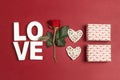 Romantic top down composition with the word love, rose, gift boxes and hearts on red background