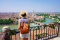 Romantic traveler girl visiting Verona city of love. Back view of young female backpacker enjoying cityscape of Verona, Italy