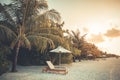 Romantic tropical sunset scenic, two sun beds, loungers, umbrella under palm tree leaves. White sand sea panorama landscape