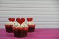 Valentines day romantic cup cakes on a pink table with white buttercream and red love heart decoration on top