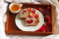 Romantic valentine`s breakfast in bed: tea, strawberry jam, whole wheat toast, jam heart, fresh strawberries and almonds , top vie