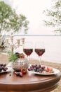 Romantic Valentine`s day dinner on the beach: two glasses of red wine, fresh fruit and a candlestick Royalty Free Stock Photo