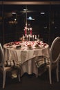 Romantic table setting with wine, beautiful flowers in box, empty glasses, rose petals and candles Royalty Free Stock Photo