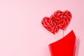 Romantic valentines day background - sweet red lollipops hearts in red corner on pastel pink color, copy space.