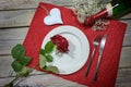 Romantic Valentines day dinner, white plate with a red rose, heart shape and a champagne bottle on a napkin and a rustic wooden Royalty Free Stock Photo