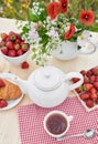 Romantic Valentines french or rural breakfast: tea, strawberries, croissants on table in poppy field. Countryside and Cozy Good Royalty Free Stock Photo