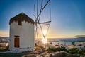 Romantic view of traditional Greek whitewashed windmill on hill. Chora town and harbor of Mykonos, Greece, low sun above Royalty Free Stock Photo