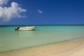 Romantic view of white boat on azure ocean against perfect blue sky and gold sand beach.