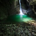 Romantic waterfall flowing through a crevasse to green lake