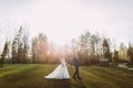 Romantic wedding couple outdoors. Bride and groom walking on green grass. Bright sun at background Royalty Free Stock Photo