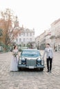 Romantic wedding couple standing in front of black retro car, beautiful happy bride and groom in summer, old city Royalty Free Stock Photo