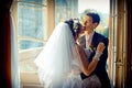 Romantic wedding portrait of attractive stylish newlyweds tenderly hugging and touching faces at the background of the