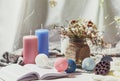 Romantic winter and New Year`s style interior view with a candle, book, garland and dryed flowers in rustic vase