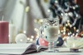 Romantic winter and New Year`s style interior view with a candle, book, garland and glass of milk