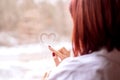 Romance and aspirations concept: red-headed woman in white shirt drawing heart on misty window Royalty Free Stock Photo