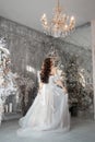 Romantic woman bride in a white wedding dress is waiting for the wedding ceremony at home. Fabulous interior, morning of the bride