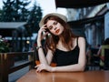 Romantic woman in a cafe on the street and bright makeup watches a white hat