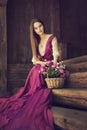 Romantic Woman Flower Bouquet in Basket. Vintage Model in Pink Fashion Dress sitting on wooden Steps