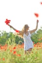 Romantic woman with a flower in her hand walking in an amazing poppy field. Warm colors of the sunset. Soft colors. Royalty Free Stock Photo