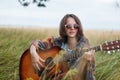 Romantic woman with short straight dark hair wearing cape and sunglasses while resting at green field enjoying beautiful landscape Royalty Free Stock Photo