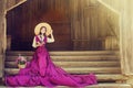 Romantic Woman in Summer Hat Long Pink Dress reading Book sitting on Steps Outside House. Rustic 19th Century Portrait Royalty Free Stock Photo