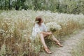 Romantic woman sitting on the footpath in a summer forest. She sits with bouquet of wild flowers in her hands Royalty Free Stock Photo