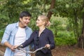 Romantic young couple with bicycle looking each other while walking in the park. Happy young woman blond hair laughing hold bike Royalty Free Stock Photo