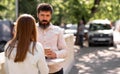 Romantic young couple drinking coffee outdoors while standing at a table in a street cafe, man and woman enjoying a Royalty Free Stock Photo