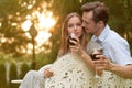 Romantic young couple having red wine on chairs in park Royalty Free Stock Photo